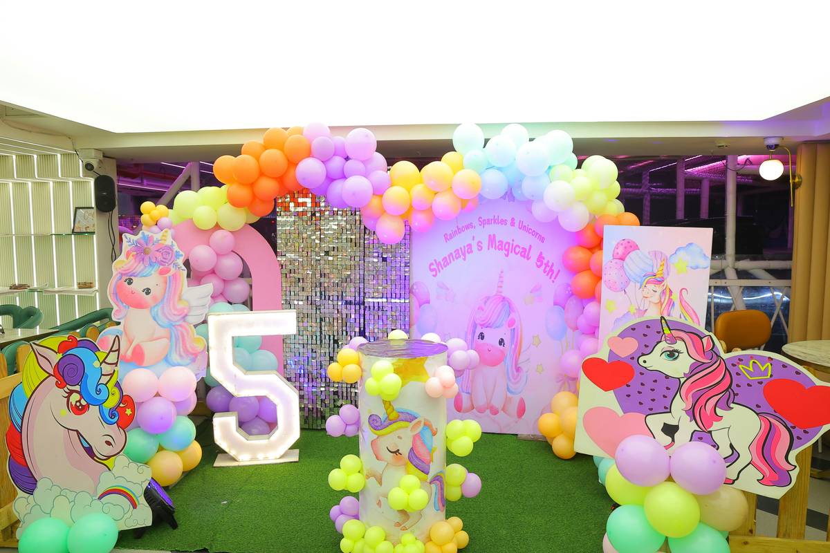 Before: plain living room. After: transformed with paper backdrop, string lights, and themed dessert table for child's birthday party